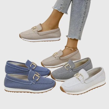 Zapatillas tipo mocasín Chiara en beige, azul y blanco, con adorno metálico dorado.