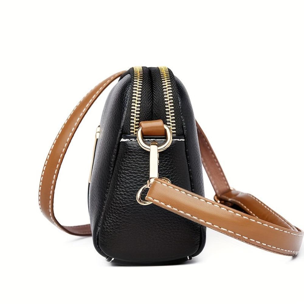 Bolso de hombro negro con textura de lichi, correa marrón y cierre de cremallera.
