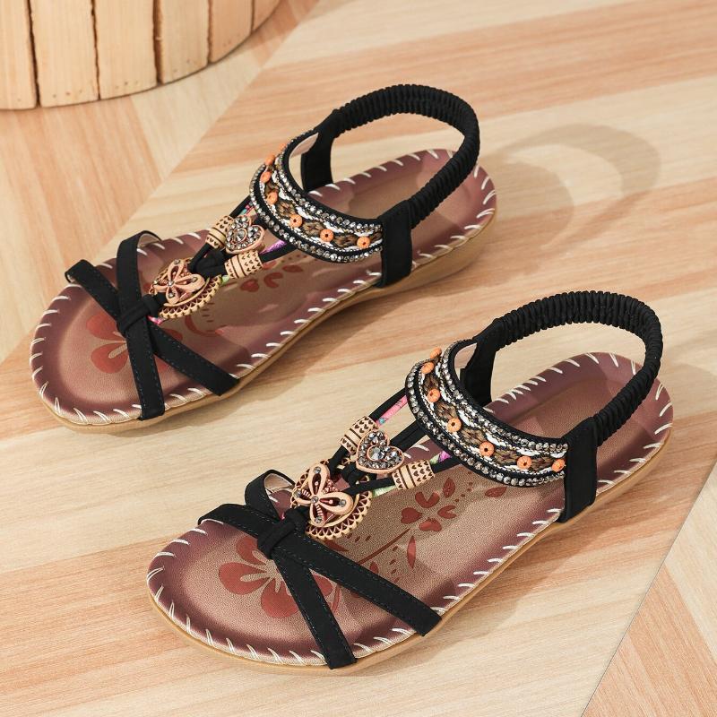 Sandalias ortopédicas estilo Ibiza marrón con tiras negras, adorno dorado y bordes decorados.