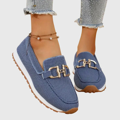 Zapatillas tipo mocasín Chiara azules con lazo metálico dorado y suela clara.
