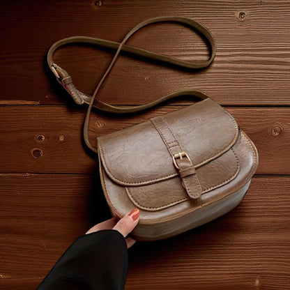 Bolso de hombro clásico de cuero beige claro con solapa y hebilla.