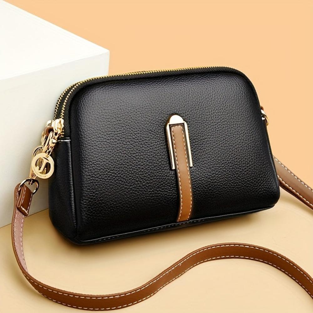 Bolso de hombro negro con textura de lichi y cierre cremallera dorado, asa ajustable.