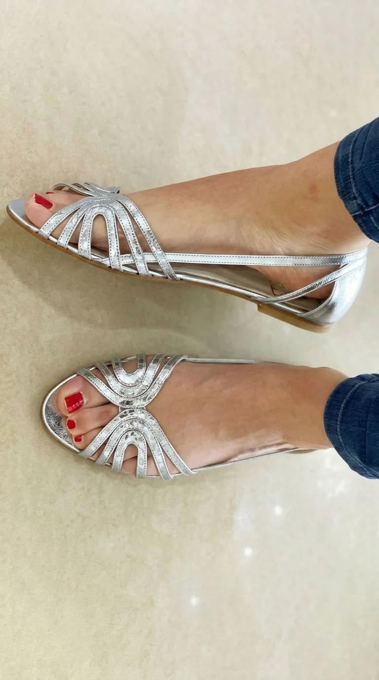 Sandalias plateadas con tiras decorativas tipo abanico y punta abierta, tacón bajo.