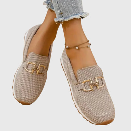 Zapatillas tipo mocasín Chiara beige con adorno metálico dorado y suela de goma.