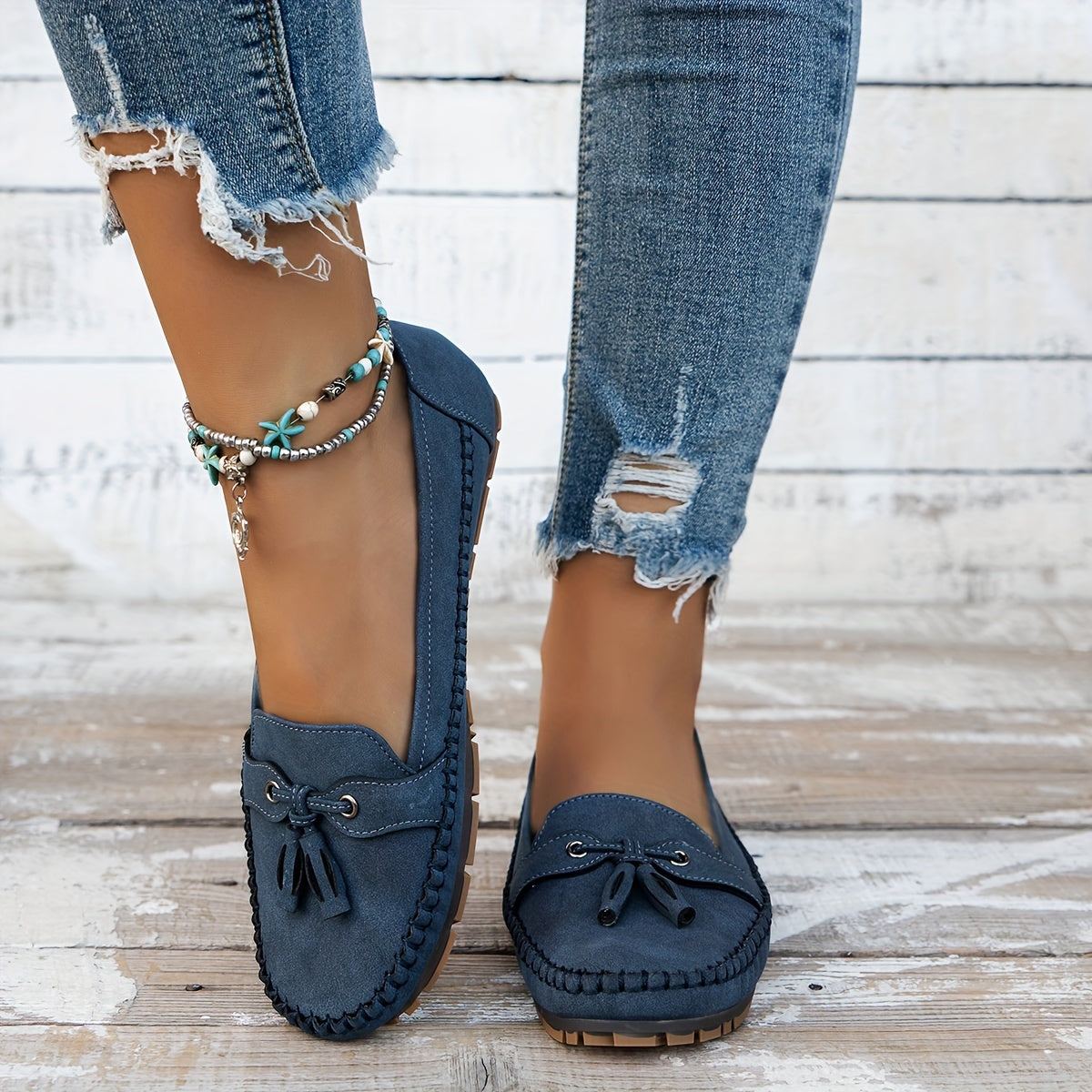 Mocasines azules de gamuza con borlas y lazo frontal; suela de goma, puestos