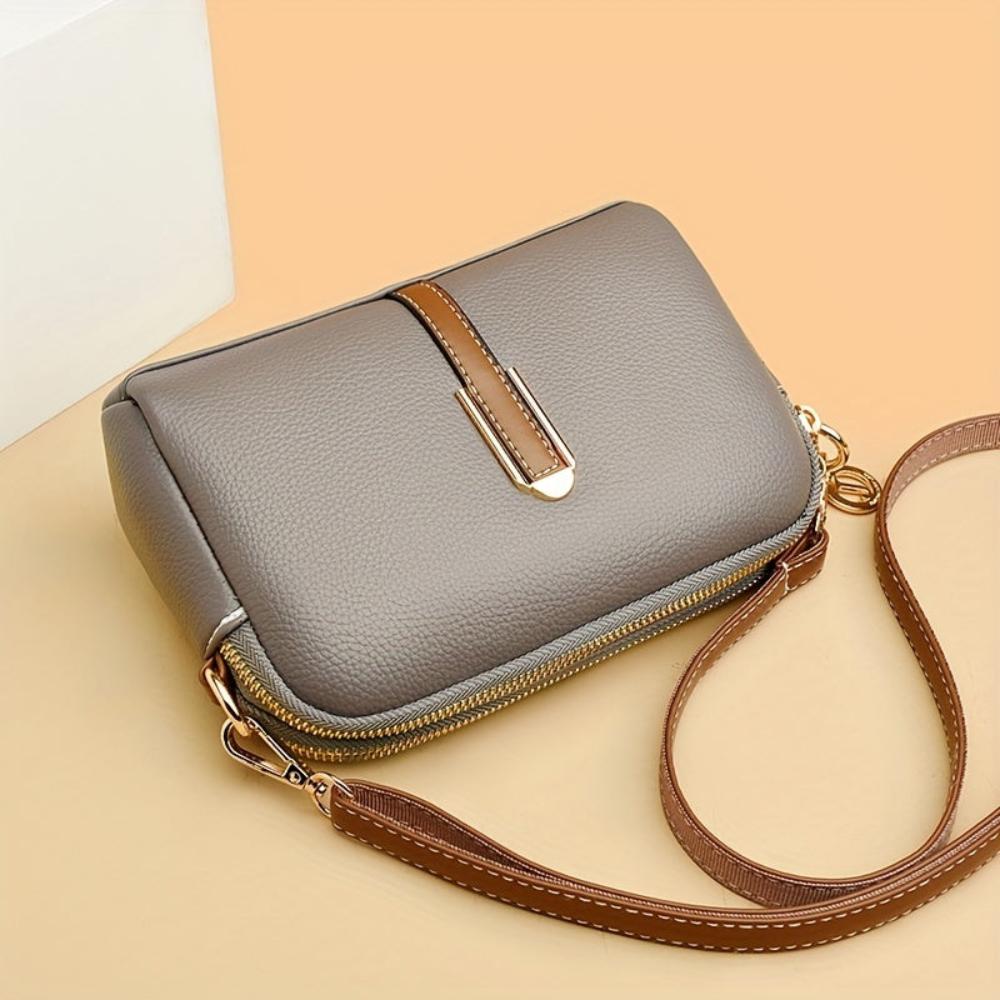 Bolso de hombro gris con textura de lichi, solapa con franja y correa marrón.