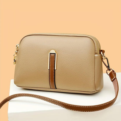 Bolso de hombro beige con textura de lichi, correa marrón y cierre cremallera metálica.