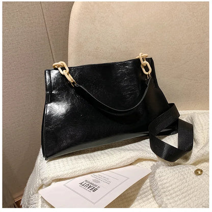 Bolso de hombro de cuero negro con asa superior y correa ancha