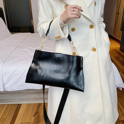 Bolso de hombro de cuero negro con asa superior y correa dorada