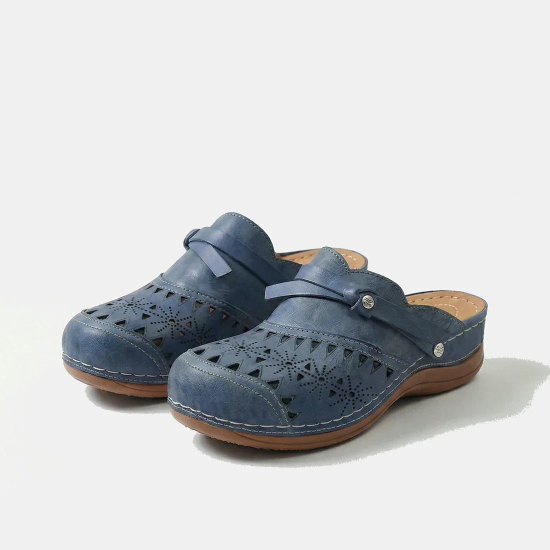 Zuecos ortopédicos azules con perforaciones y tira con cierre metálico sobre suela de cuña