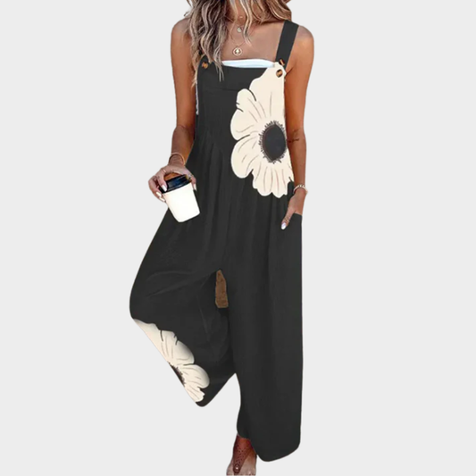 Salopette de mujer negra sin mangas con tirantes anchos y estampado floral blanco.