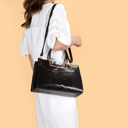 Bolso de cuero negro con cartera a juego, asa rígida y correa colgante, textura tipo cocodrilo