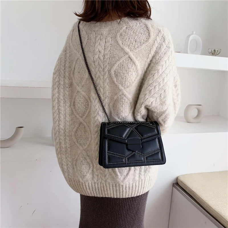 Bolso de hombro negro de PU con cadena y tachuelas, llevado al hombro