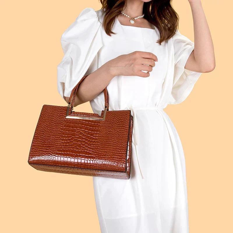 Bolso de cuero marrón con asa superior y cartera a juego, textura tipo cocodrilo