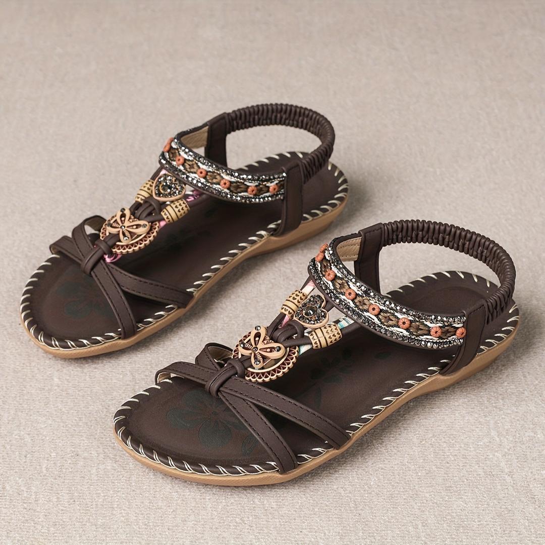 Sandalias ortopédicas Ibiza marrón oscuro con tiras elásticas negras y adorno dorado.