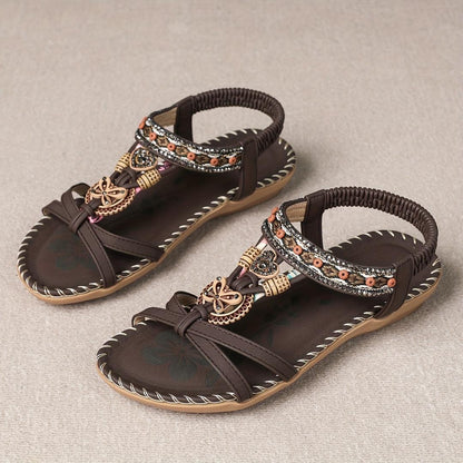 Sandalias ortopédicas Ibiza marrón oscuro con tiras elásticas negras y adorno dorado.