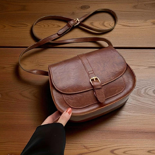Bolso de hombro clásico de cuero marrón con solapa y correa ajustable.