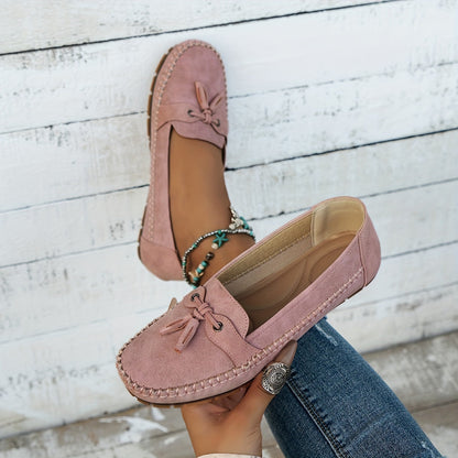 Mocasines rosa de gamuza con borlas y lazo frontal; punta y costuras laterales visibles