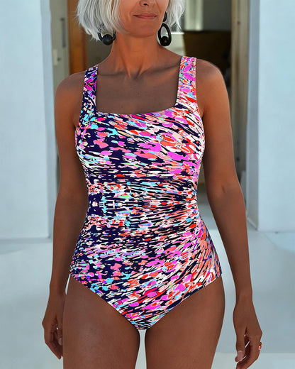 Traje de baño de una pieza con tirantes y estampado multicolor con tonos rosa y azul.