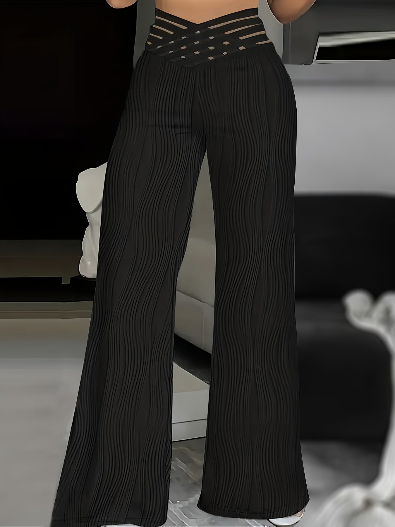 Pantalones negros de cintura alta cruzados, con rayas verticales onduladas y pernera ancha