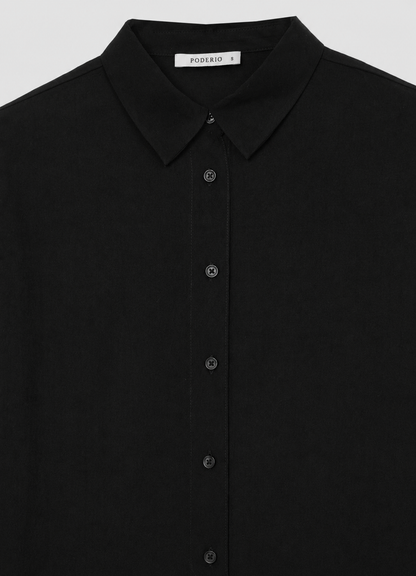 Camisa negra lisa: cuello y botonera con botones discretos.
