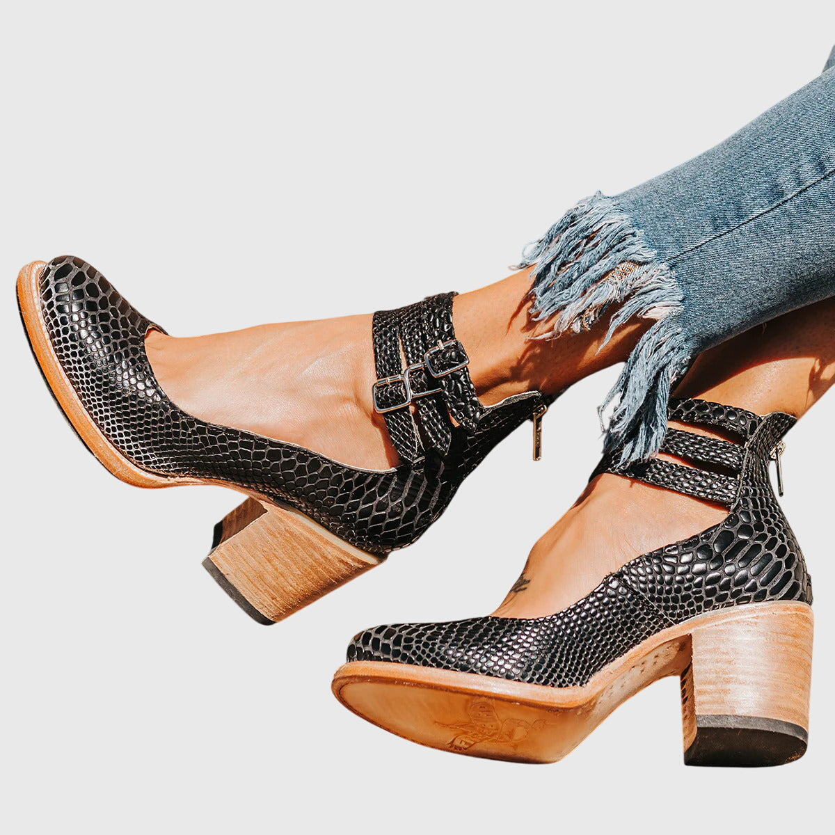 Zapatos de tacón negros tipo serpiente con cierre de hebilla y tacón cuadrado.