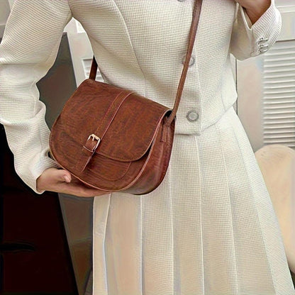 Bolso de hombro clásico de cuero marrón con solapa y hebilla metálica.