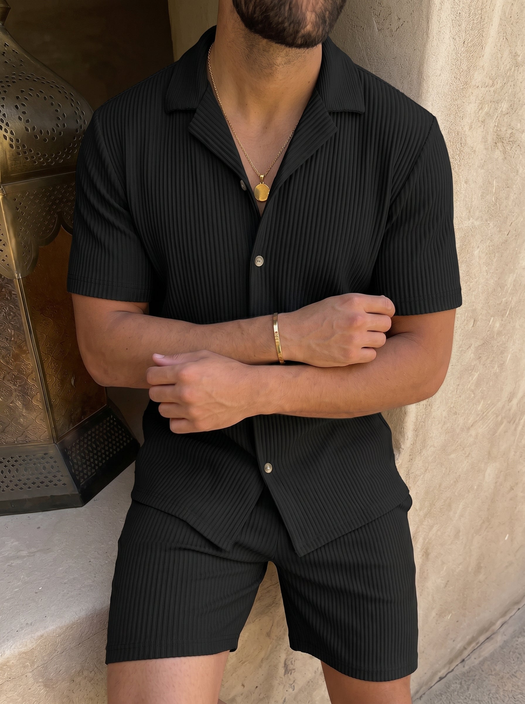 Conjunto negro a rayas verticales: camisa de botones y bermudas, puños visibles