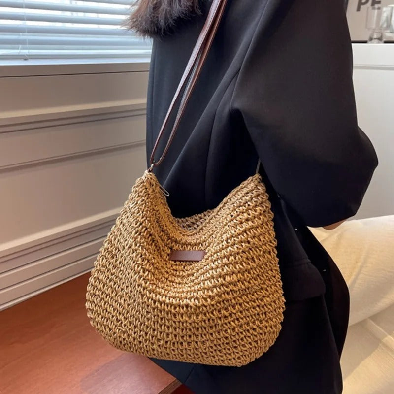 Bolso bandolera de paja caqui con correa marrón larga y bolsillo frontal con placa