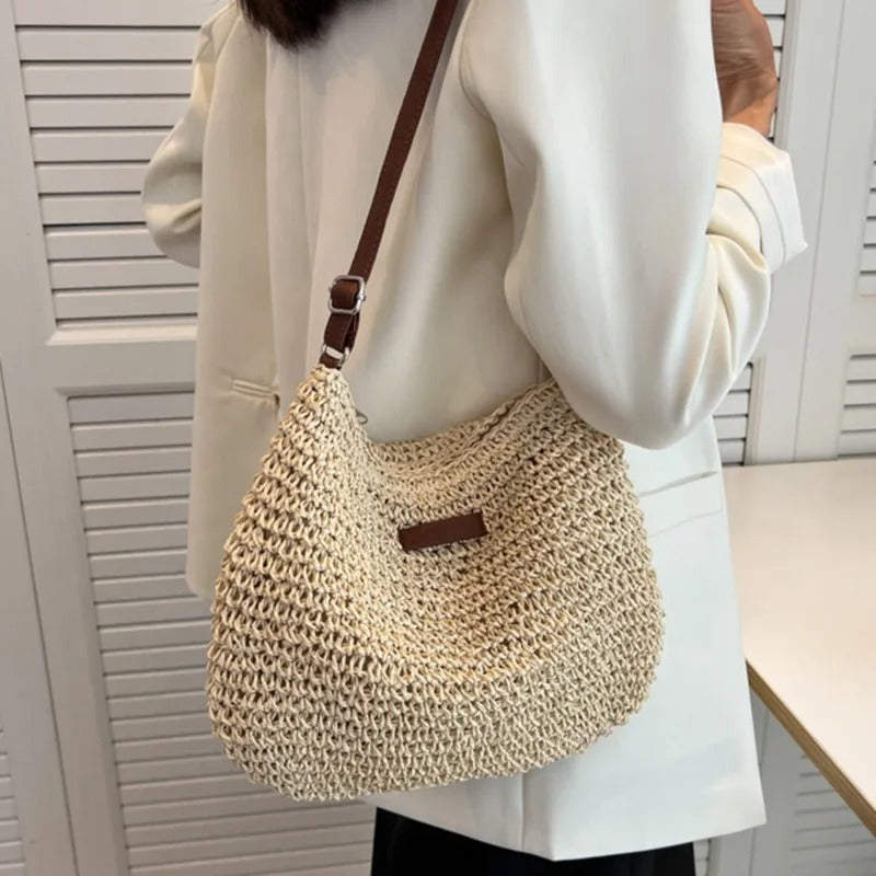 Bolso bandolera de paja beige con correa marrón, forma de medio saco y placa