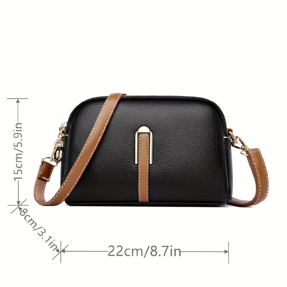 Bolso de hombro negro con textura de lichi, correa marrón y placa central, medidas incluidas.