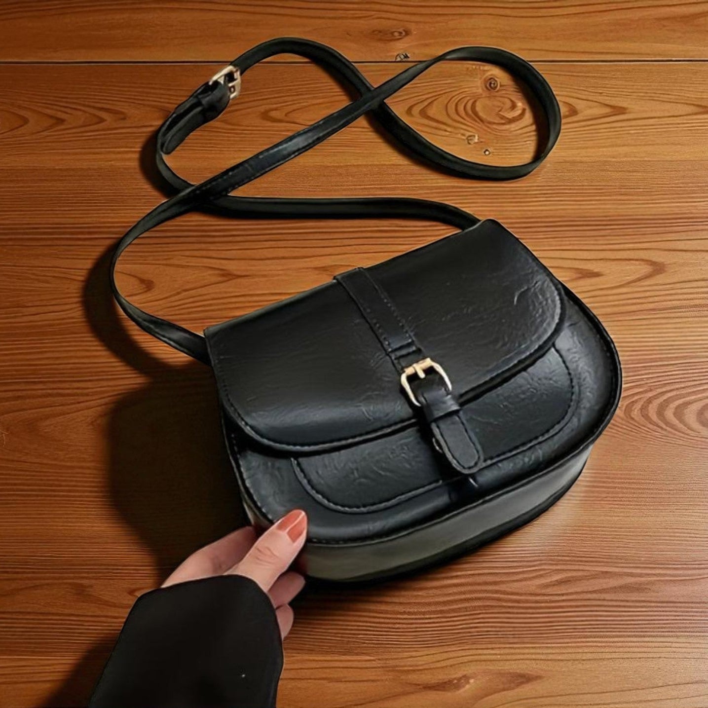 Bolso de hombro clásico de cuero negro con solapa redondeada y cierre metálico.