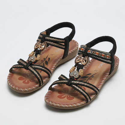 Sandalias ortopédicas Ibiza marrón con tiras negras trenzadas y adorno dorado con abalorios.
