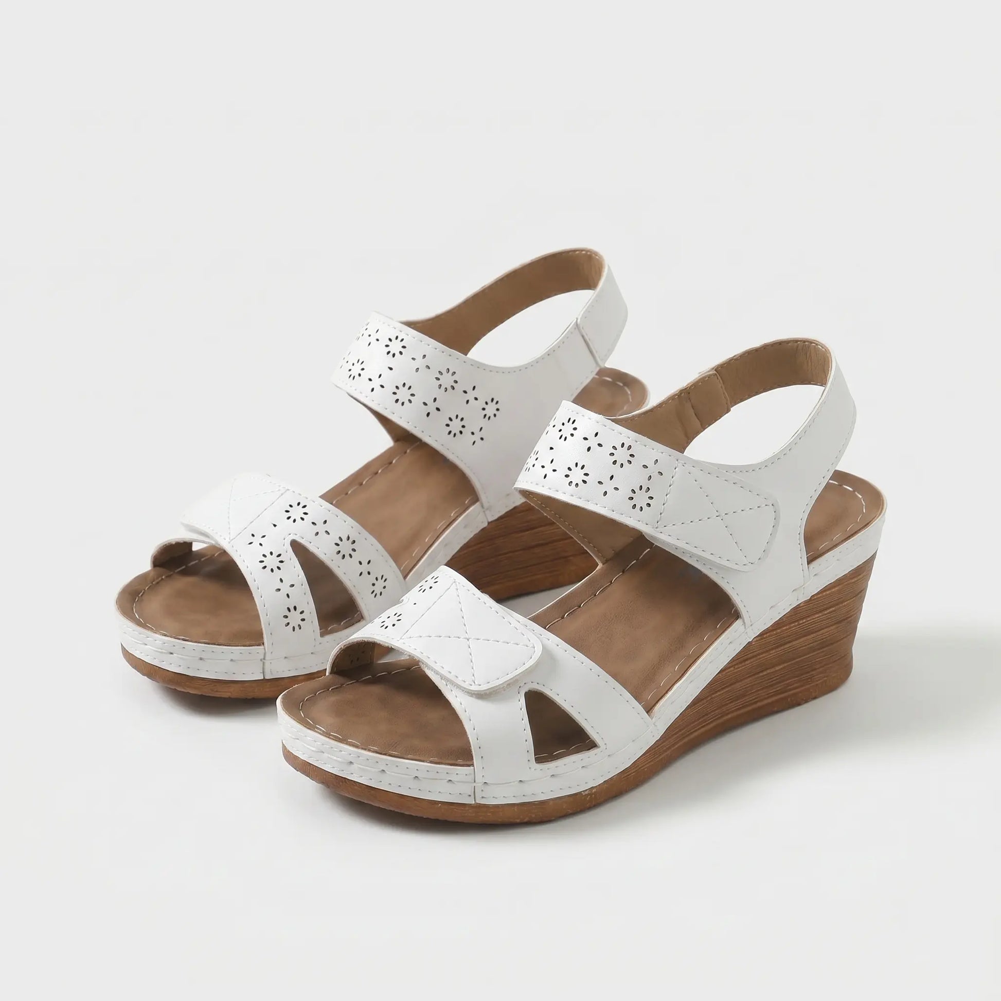 Sandalias ortopédicas blancas con perforaciones, cierre al tobillo y cuña de madera