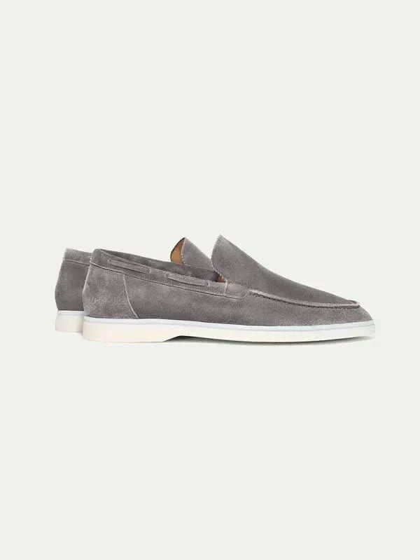 Mocasines de ante gris, slip-on, con suela blanca y forro anaranjado.