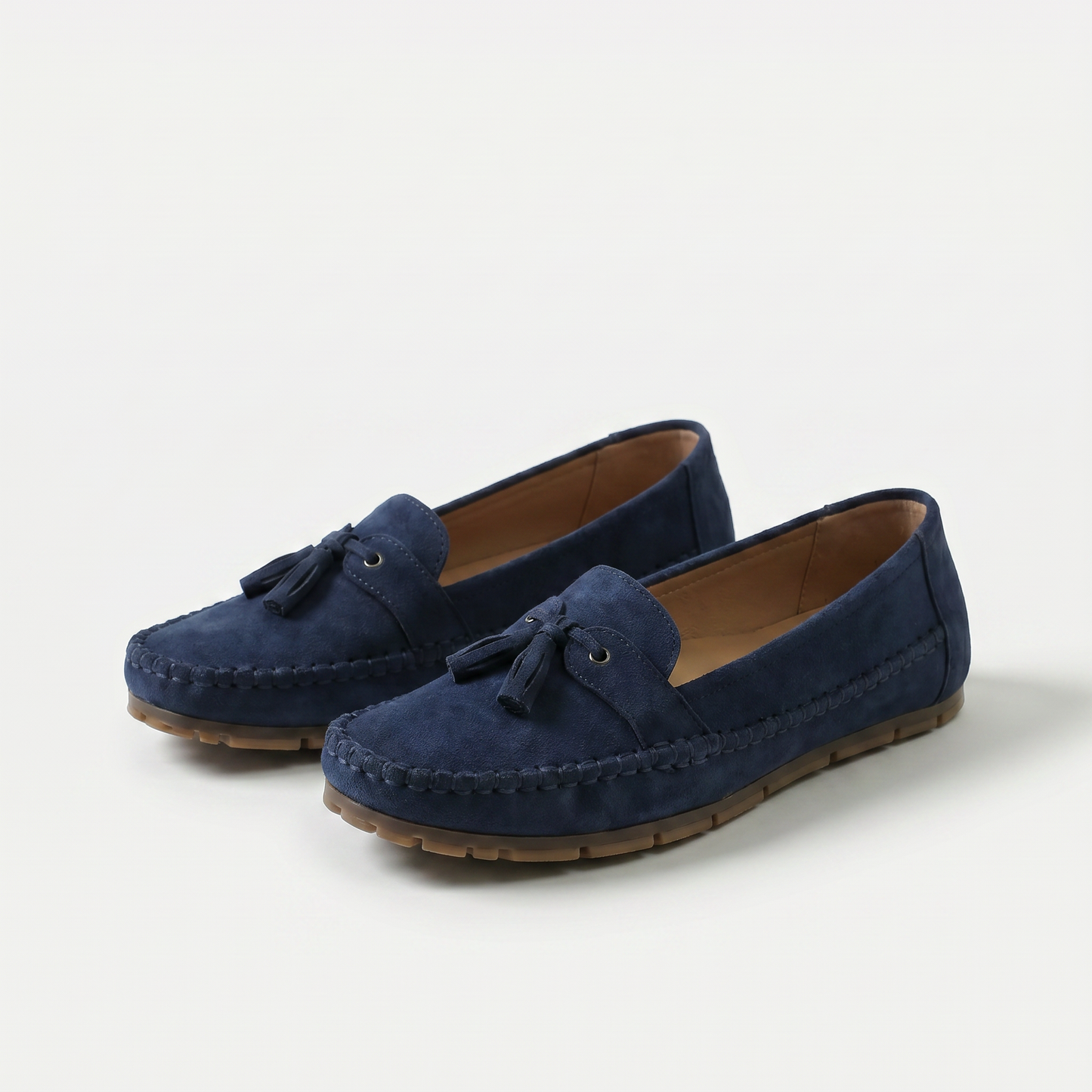 Mocasines azules de gamuza con borlas y lazo frontal, costuras visibles y suela dentada