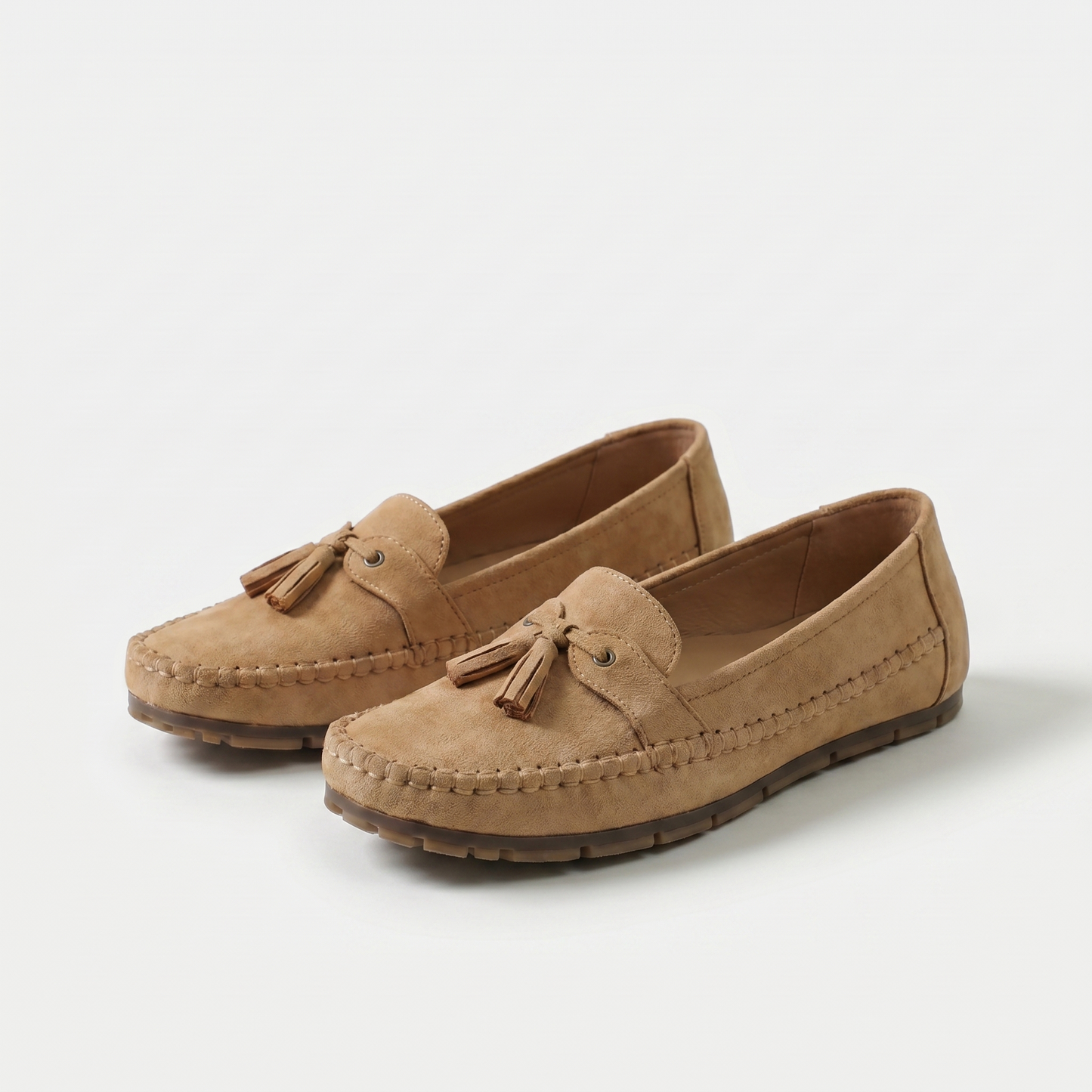 Mocasines marrón-caramelo de gamuza con borlas y lazo frontal, costuras visibles y suela