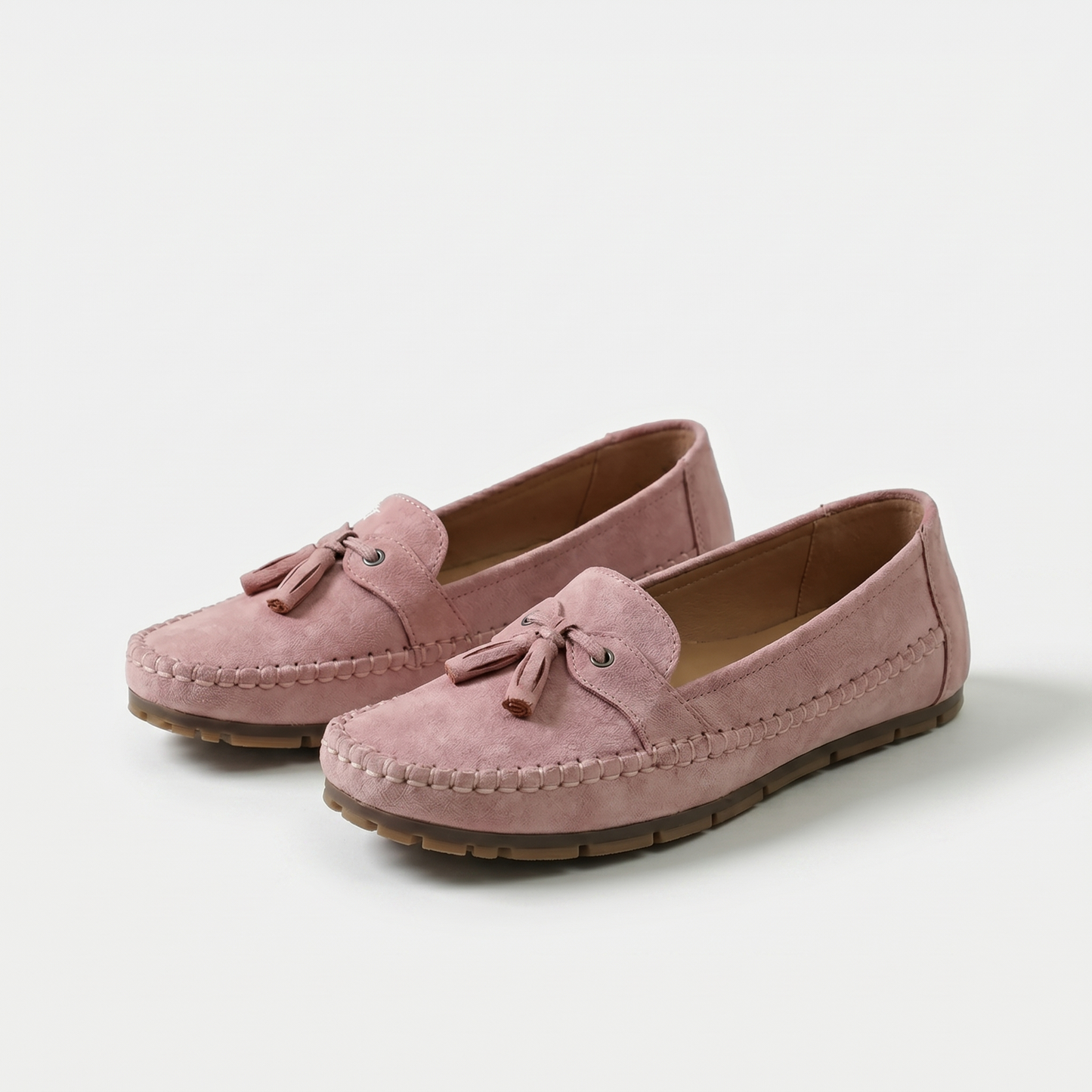Mocasines rosa de gamuza con borlas y lazo frontal, costuras visibles y suela de goma