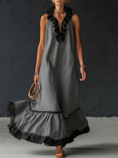 Vestido largo sin mangas gris con volantes negros en el escote y falda con ribete
