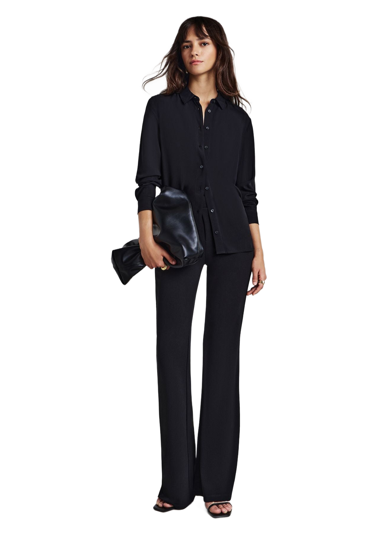 Camisa negra lisa abotonada de manga larga, en modelo con pantalón oscuro.