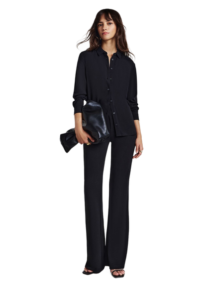 Camisa negra lisa abotonada de manga larga, en modelo con pantalón oscuro.