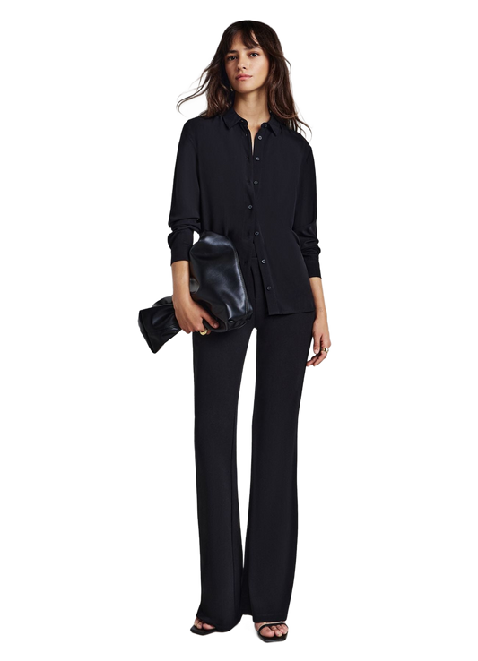 Camisa negra lisa abotonada de manga larga, en modelo con pantalón oscuro.
