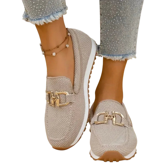 Zapatillas tipo mocasín Chiara beige con adorno metálico dorado y suela beige.