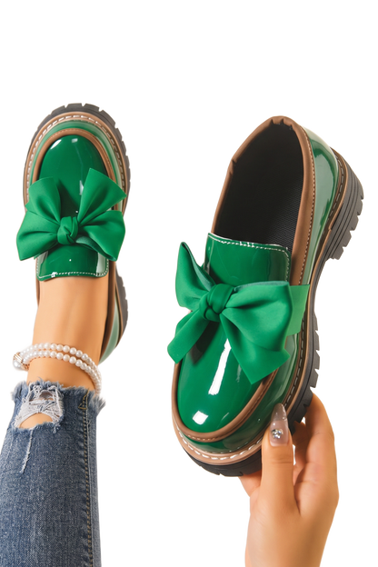 Mocasines con lazo verde brillante y suela gruesa negra, con detalles metálicos.