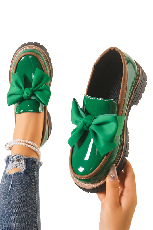 Mocasines con lazo verde brillante y suela gruesa negra, con detalles metálicos.