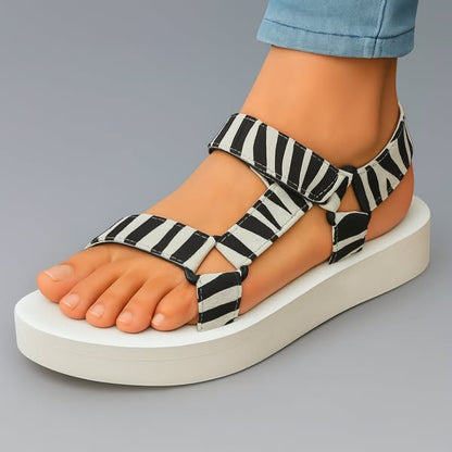 Sandalias ortopédicas con estampado cebra negro y blanco, plataforma blanca y tiras ajustables.