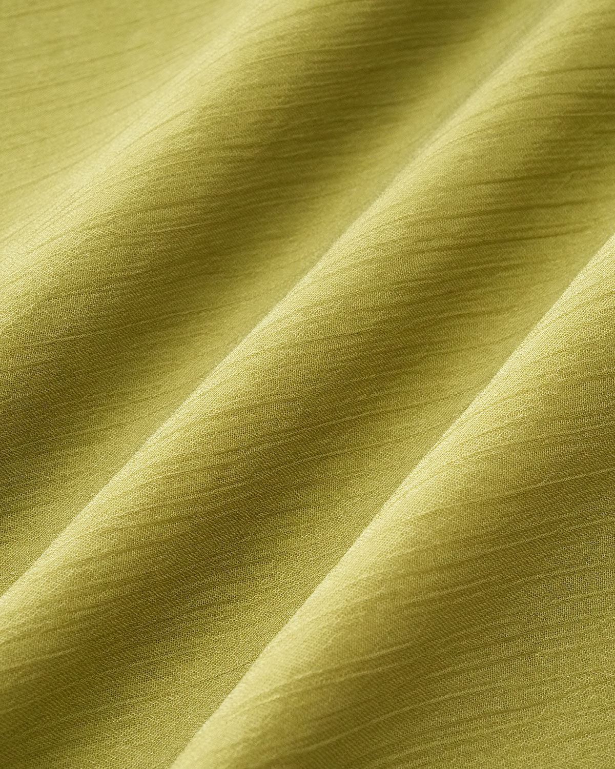 Tela verde del vestido con textura lisa y caída ondulada